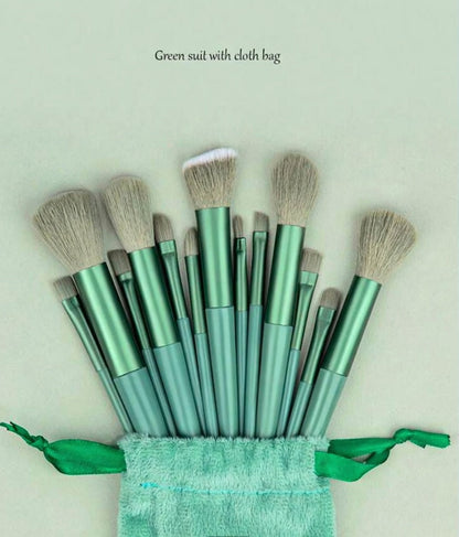 Set of green makeup brushes with a matching cloth bag on a light green background.