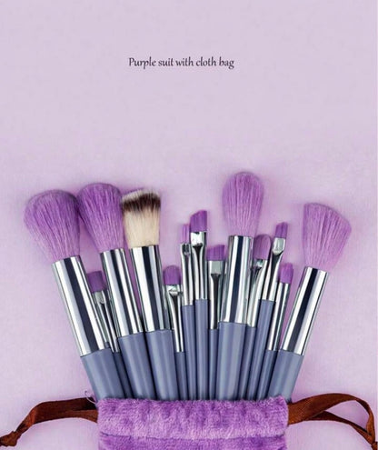 Set of makeup brushes with purple bristles in a purple bag on a light pink background