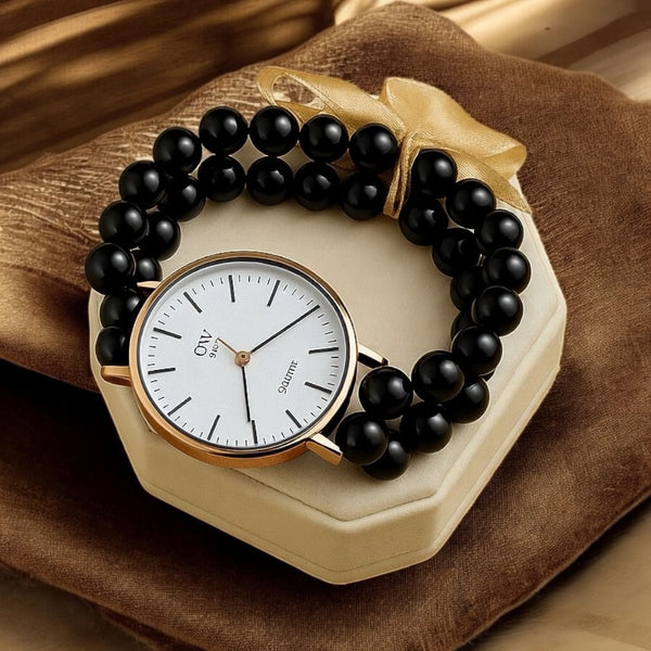 Black beaded bracelet with a gold watch face on a brown fabric background