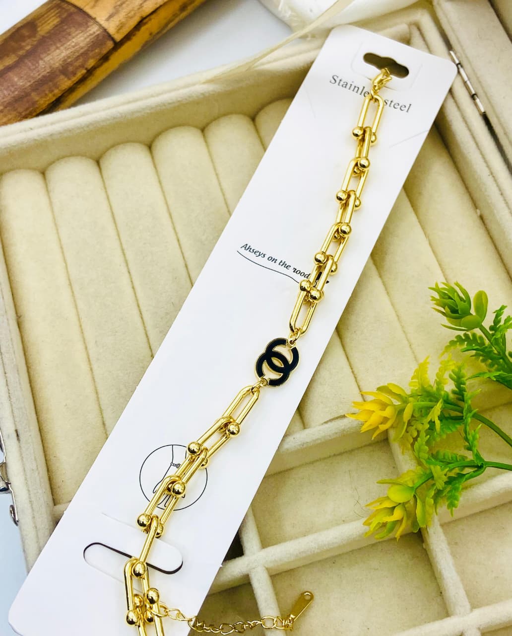 Gold bracelet on a white card with a decorative background