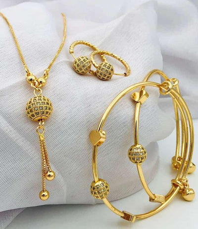 Gold jewelry set including necklace, bracelet, and ring on a white fabric background
