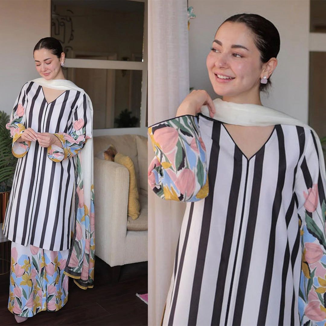 Woman wearing a black and white striped dress with floral patterns in a living room setting.