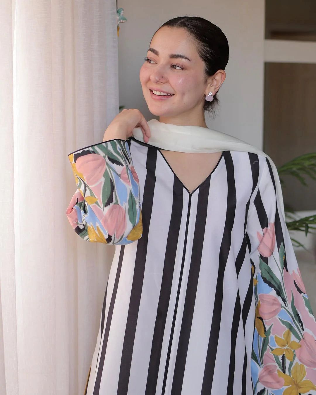 Woman wearing a black and white striped dress with floral sleeves indoors.