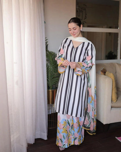 Woman wearing a black and white striped dress with floral patterns indoors.