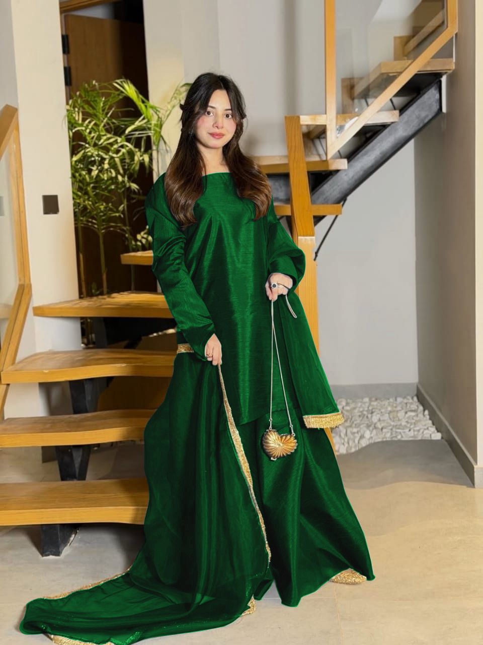 Woman in a green traditional outfit standing in a home interior.