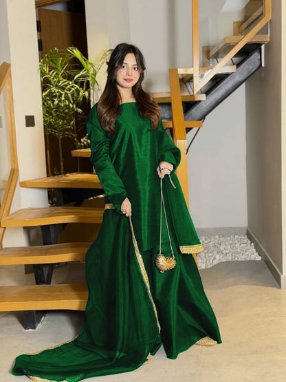 Woman in a green traditional outfit standing in a home interior.