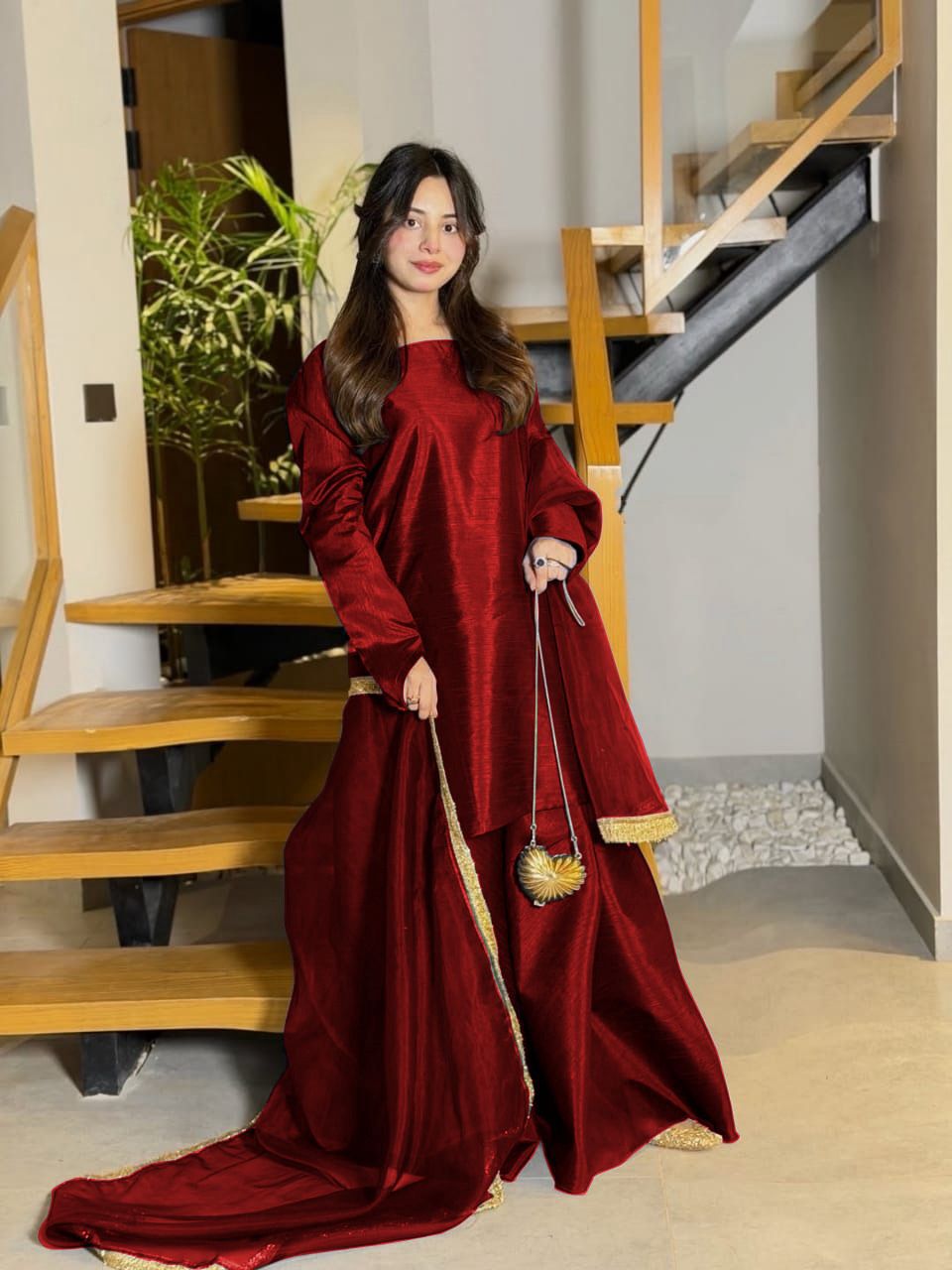 Woman in a long red dress standing in a home interior.