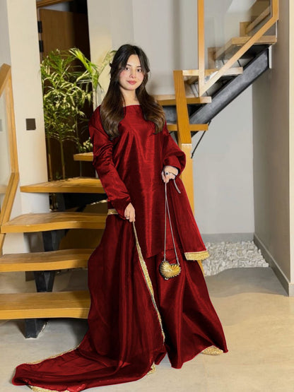 Woman in a long red dress standing in a home interior.