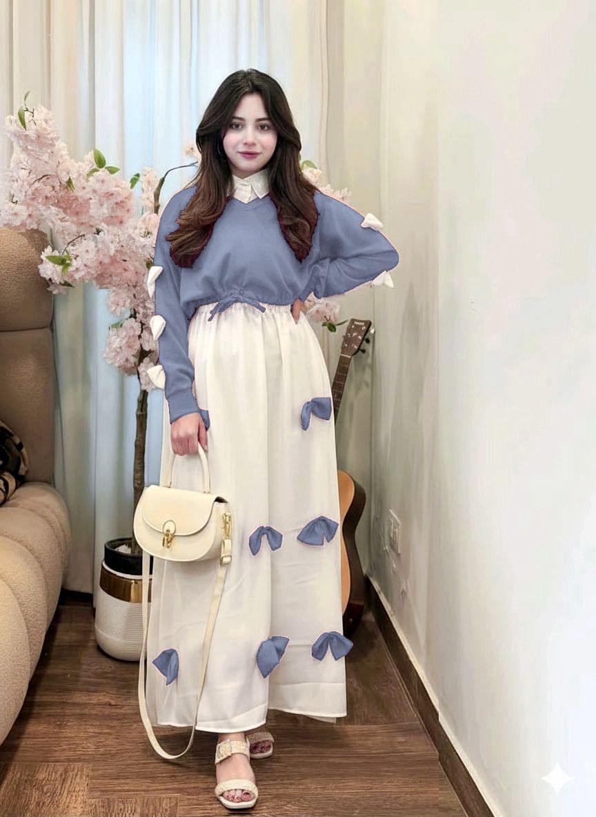 Woman wearing a blue sweater and white dress with blue floral patterns in a living room.