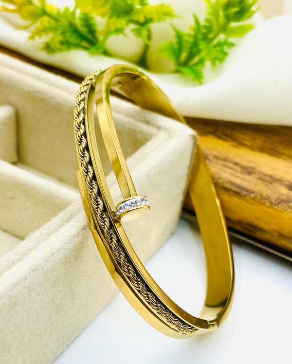 Gold bracelet with intricate design on a white surface