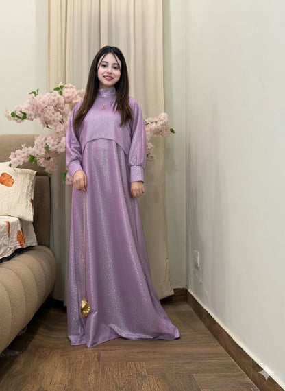 Woman in a long purple dress standing in a room with floral decorations.