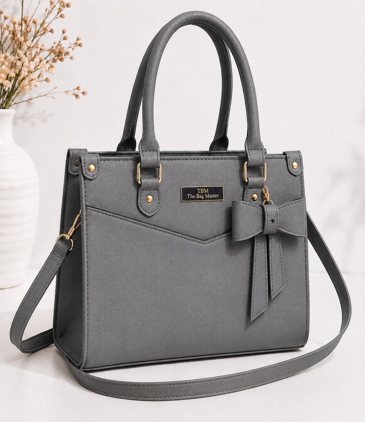 Gray handbag with a bow detail on a white background