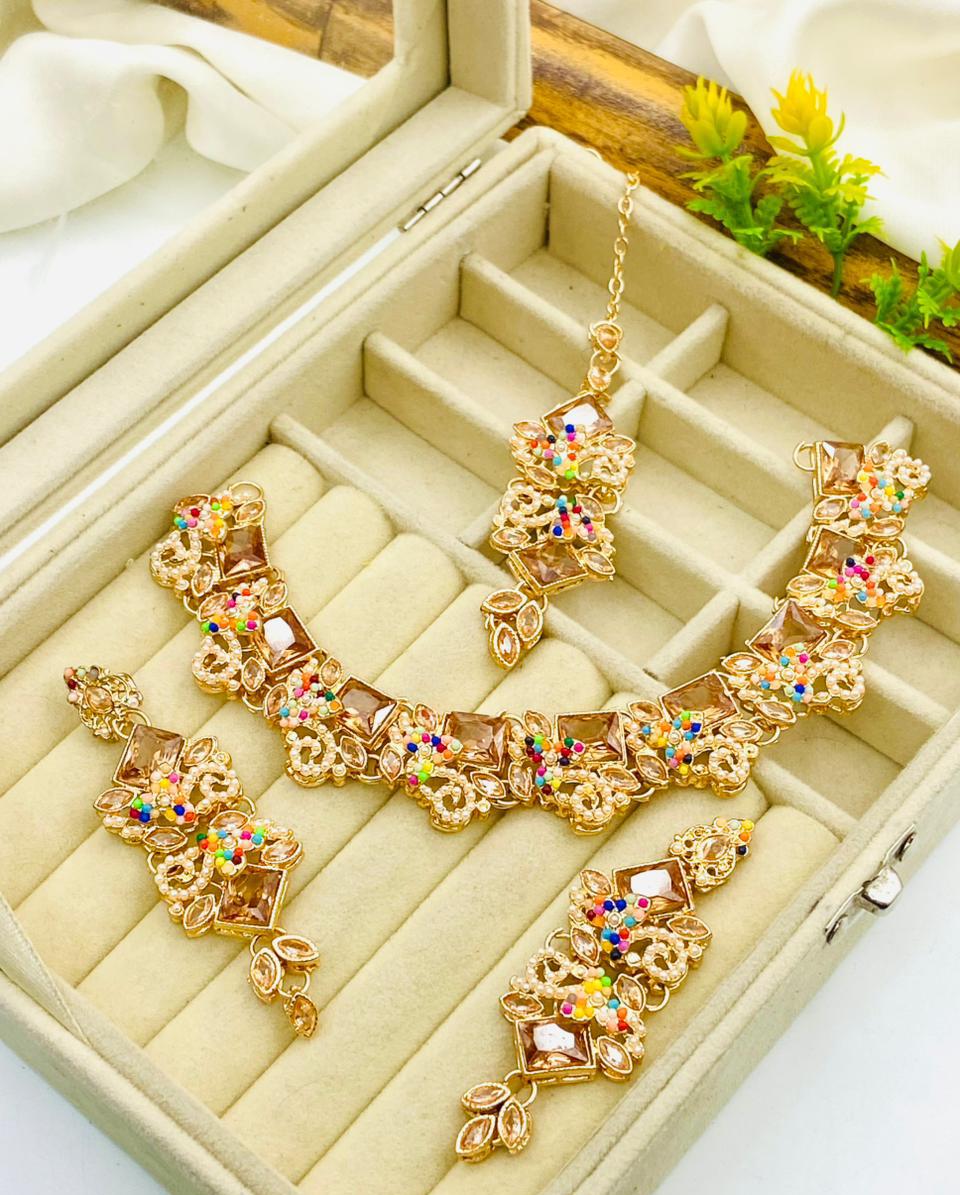 Gold necklace with colorful stones on a beige jewelry box