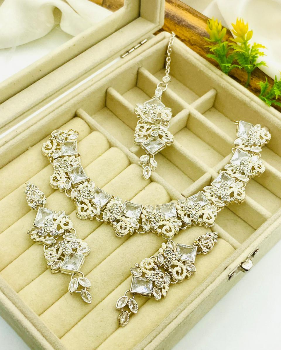 Silver jewelry set with necklace and earrings on a beige jewelry box.