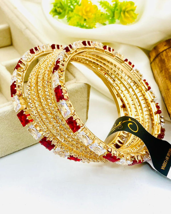 Gold and red bangles on a white surface with a blurred background
