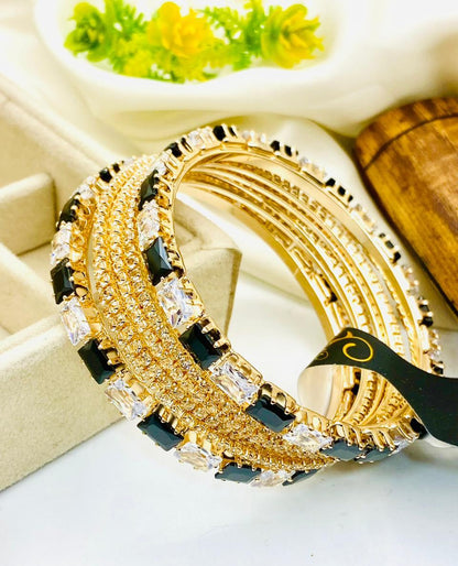 Gold and black bracelet with clear stones on a white surface