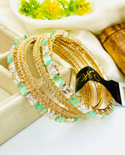 Gold and green beaded bracelets on a white surface with a blurred background