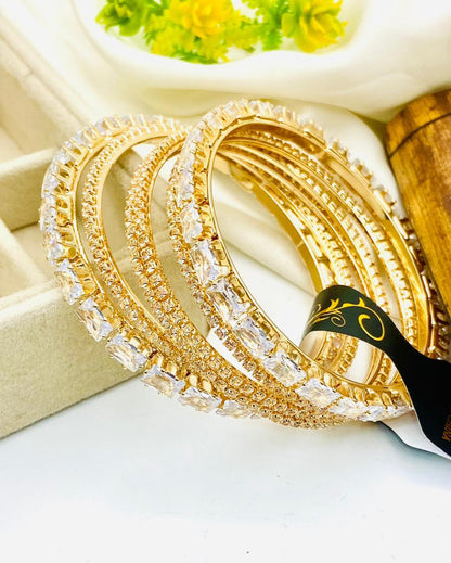 Gold bangles with clear stones on a white surface