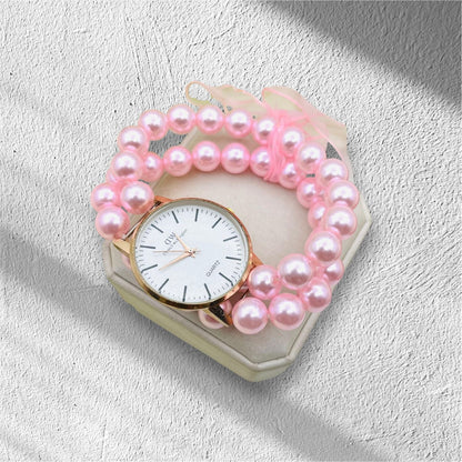 Pink pearl bracelet with a watch on a textured surface