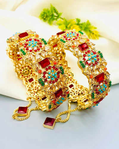 Gold bracelets with colorful gemstones on a light background
