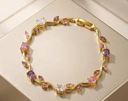 Gold bracelet with pink and purple gemstones on a beige background