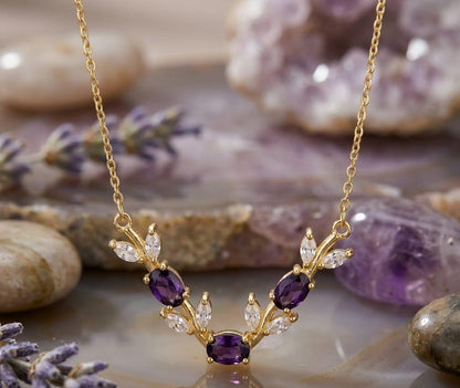 Gold necklace with purple gemstones on a natural stone background