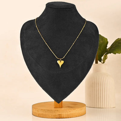 Gold heart necklace on a black mannequin bust with a beige background