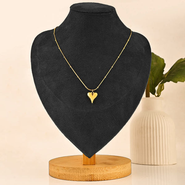 Gold heart necklace on a black mannequin bust with a beige background