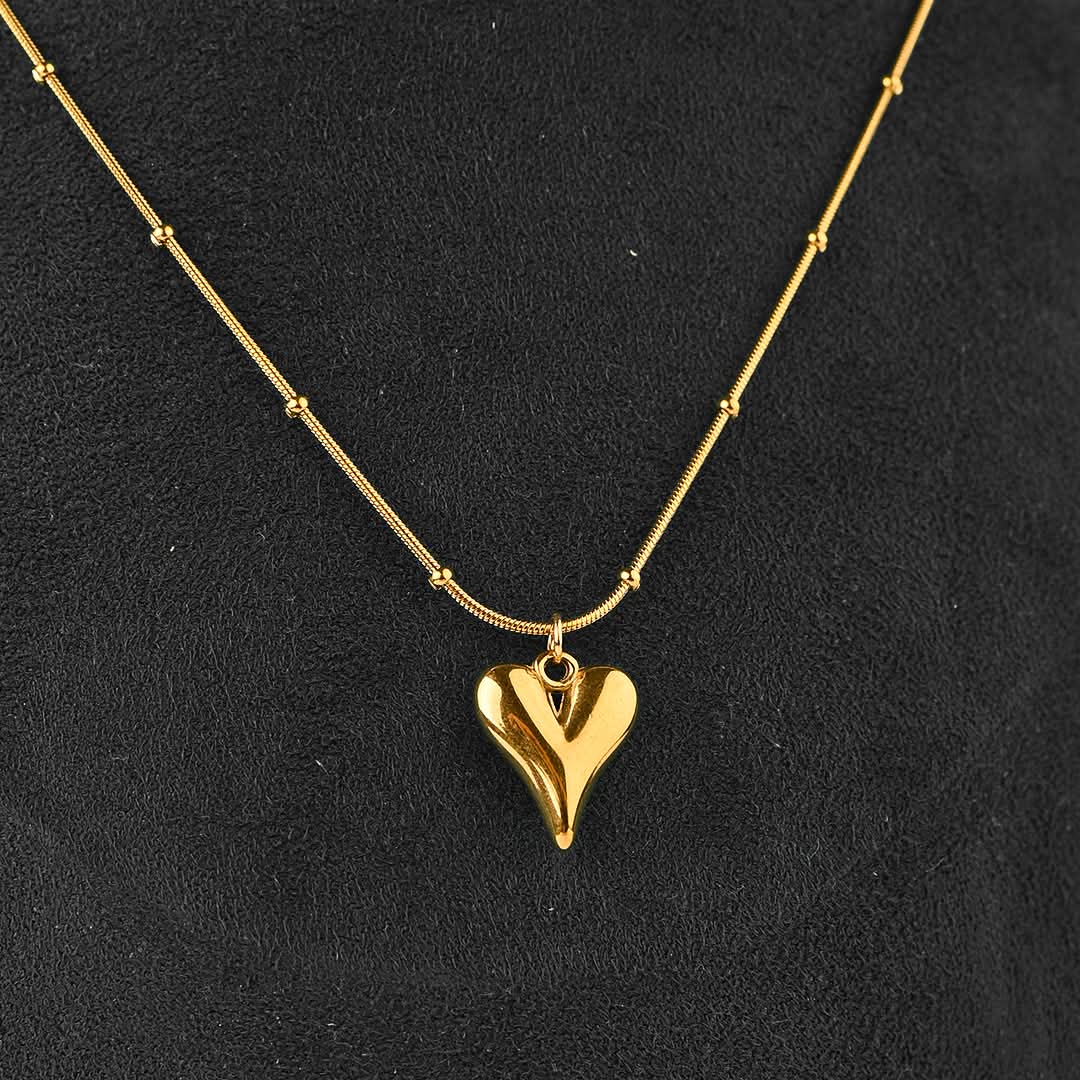 Gold heart-shaped pendant necklace on a black background