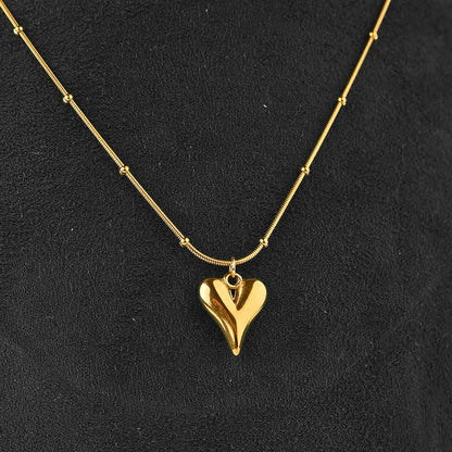 Gold heart-shaped pendant necklace on a black background